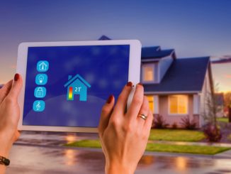 Smart Home Tablet und im Hintergrund steht ein Haus