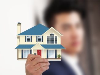 Ein Immobilienmakler hält ein Haus in der Hand