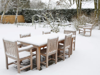 Gartenmöbel stehen von Schnee bedeckt im Garten