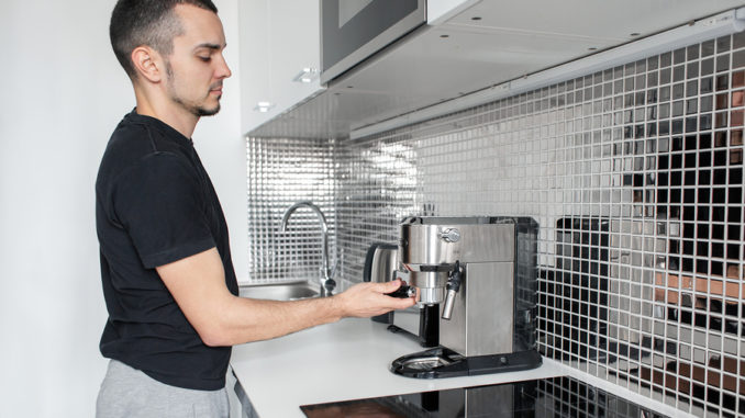 Mann bedient Kaffeevollautomat zuhause