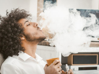 Ein junger Mann mit Afro raucht in der eigenen Wohnung