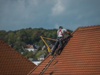 Handwerker ist gesichert auf Dach und arbeitet.