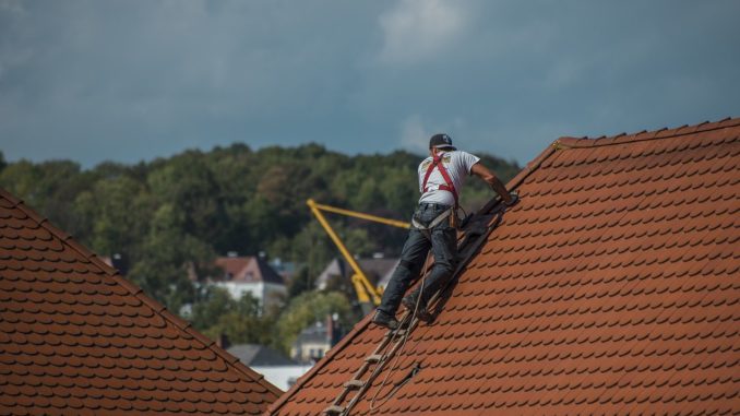 Handwerker ist gesichert auf Dach und arbeitet.