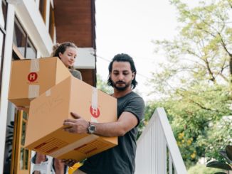 Zwei Leute tragen Umzugskartons die Treppe herunter